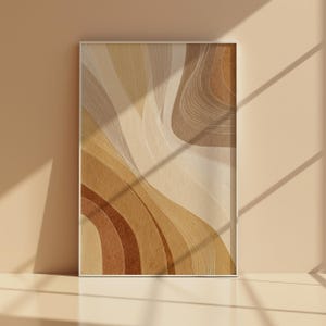 May include: Abstract art print with a flowing design in beige, tan, and brown tones. The artwork has a layered effect with curved lines and shapes, creating a sense of movement. The print is framed in a simple, neutral-toned frame.