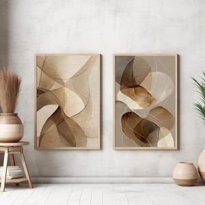Könnte beinhalten: Zwei gerahmte abstrakte Kunstdrucke mit neutralen Braun- und Beigetönen. Das Kunstwerk zeigt fließende, organische Formen. Ein Holzschemel hält eine Vase mit getrockneten Pflanzen. Eine Topfpflanze und eine kleine Vase sind ebenfalls vorhanden.