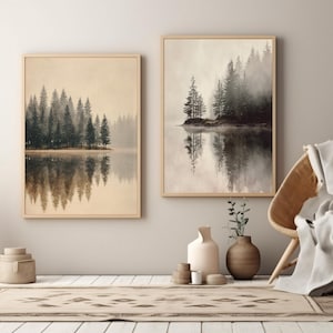 Può includere: Due stampe artistiche incorniciate raffiguranti una serena scena lacustre con alberi sempreverdi e i loro riflessi. L'opera d'arte ha una palette di colori neutri con toni beige e grigi. Le stampe sono esposte in una stanza accogliente dai toni neutri.