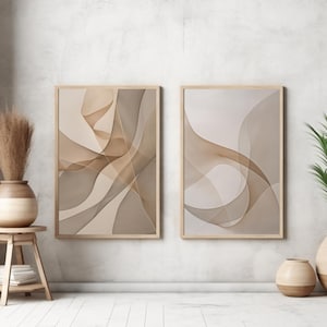 Könnte beinhalten: Zwei gerahmte abstrakte Kunstdrucke mit fließenden, geschichteten Designs in Beige- und Brauntönen hängen an einer hellgrauen Wand. Ein Holzschemel hält eine Vase mit getrockneten Pflanzen. Eine Topfpflanze und eine dekorative Vase stehen auf dem Boden.