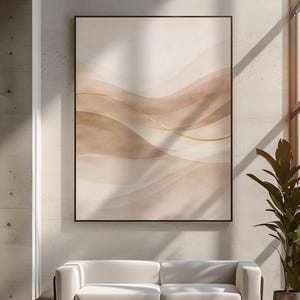 Könnte beinhalten: Abstrakter Kunstdruck mit geschichteten, fließenden Formen in Beige- und Brauntönen, akzentuiert durch eine dünne goldene Linie. Das Kunstwerk ist in Schwarz gerahmt und hängt über einem weißen Sofa in einem modernen Wohnraum. Der Raum hat eine Betonwand und ein großes Fenster.