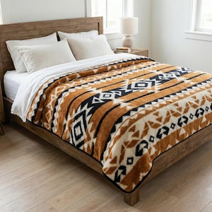 May include: A plush, patterned blanket in shades of brown, black, and cream, draped over a wooden bed frame. The blanket features a geometric design with stripes and diamond shapes, creating a cozy and inviting aesthetic.