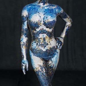Può includere: Una tuta integrale caratterizzata da un motivo a specchio a mosaico riflettente nei toni del blu, argento e bianco. Il capo copre l'intero corpo, inclusi testa, braccia e gambe, con una silhouette aderente. Il testo recita SPANDEX HALLOWEEN.