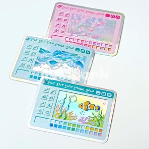 May include: Three holographic stickers with a computer interface design. Each sticker features a different image: cherry blossoms, a mountain landscape, and a clownfish in an aquarium. The stickers have the text "FILE EDIT VIEW IMAGE HELP".