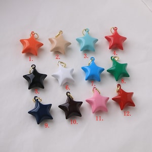 Puede incluir: Una colección de doce colgantes en forma de estrella en varios colores, incluyendo naranja, beige, turquesa, rojo, negro, blanco, azul, verde, marino, marrón, rosa y rojo oscuro. Cada colgante tiene un lazo dorado.