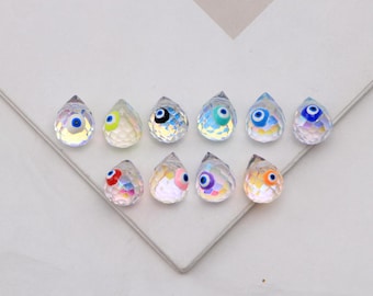 Conjunto de 5 pingentes de contas de vidro em formato de gota d'água, com detalhes de olhos de cristal esmaltado, ideais para confecção de pulseiras e colares de miçangas.