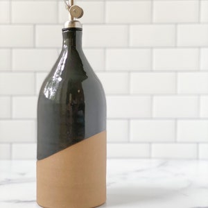 K&ouml;nnte beinhalten: Eine schwarze und braune Keramikflasche f&uuml;r &Ouml;l und Essig mit einem silbernen Ausgie&szlig;er.