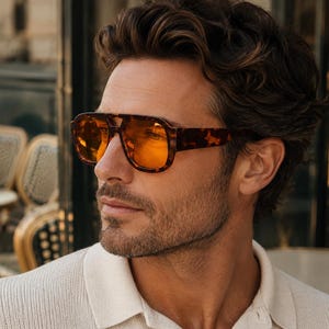 Può includere: Occhiali da sole con motivo tartarugato caratterizzati da una montatura spessa e audace con design a doppio ponte e lenti colorate arancioni vivaci. Gli occhiali hanno una forma classica ispirata agli aviatori con aste larghe e finitura lucida.