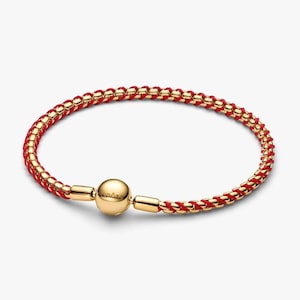 May include: Gold-toned bracelet with a woven red and gold chain design. The bracelet features a gold clasp with a spherical center. The overall design is a blend of red and gold, creating a striking contrast.