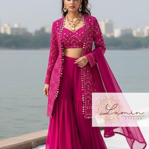 May include: A vibrant fuchsia ensemble featuring a crop top, palazzo pants, and a long jacket with intricate embroidery. The outfit includes a matching sheer scarf and gold jewelry. The Lumin Atelier logo is visible.