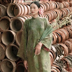 Peut inclure: Une tunique vert olive &agrave; manches longues avec un col officier et un motif jacquard ton sur ton subtil. Le v&ecirc;tement pr&eacute;sente des manches larges et une silhouette droite, confectionn&eacute; dans un tissu textur&eacute; avec un l&eacute;ger &eacute;clat &agrave; la lumi&egrave;re.