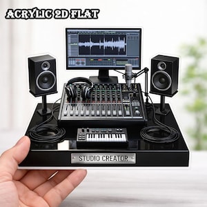 May include: A black acrylic 2D flat studio setup with a computer monitor displaying audio waveforms, a mixing console, speakers, headphones, a microphone, and a small keyboard. The text "STUDIO CREATOR" is on a silver plate.