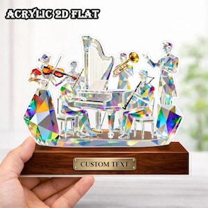 May include: An acrylic 2D flat art piece depicting an orchestra with a harp, piano, and other instruments. The musicians are rendered in a geometric, faceted style with colorful, iridescent details. The base is a dark wood with a metal plate that reads "CUSTOM TEXT".