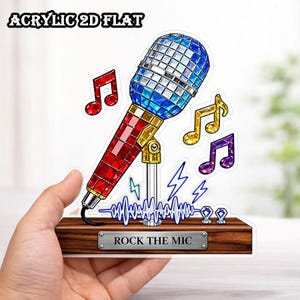 May include: A colorful acrylic 2D flat microphone design with a blue and silver disco ball top, red body, and gold accents. Includes musical notes, lightning bolts, and the text "ROCK THE MIC" on a wooden base.