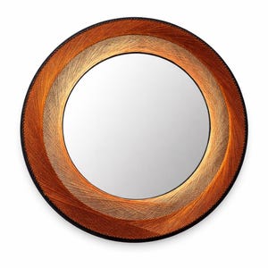 May include: Round mirror with a woven design. The frame features concentric rings of orange, tan, and black. The mirror's center is a reflective surface. The woven texture adds a unique, handcrafted aesthetic to this decorative wall mirror.