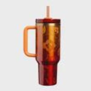 May include: A tall, cylindrical tumbler in a deep gradient of red and orange, featuring a sturdy side handle, a matching lid, and a central straw. The exterior surface displays a repeating pattern of circular motifs in a lighter, golden-orange hue.