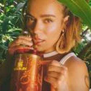 May include: A copper-colored insulated tumbler featuring a prominent Stanley brand logo in gold lettering on the front. The cylindrical vessel includes a sturdy side handle and a matching lid, showcasing a metallic finish with a reflective surface.
