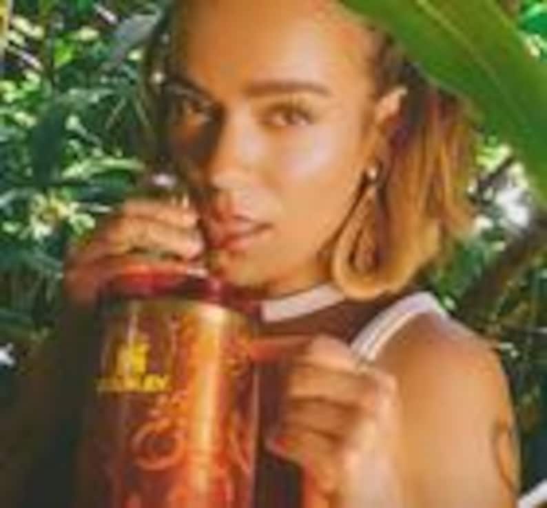 May include: A copper-colored insulated tumbler featuring a prominent Stanley brand logo in gold lettering on the front. The cylindrical vessel includes a sturdy side handle and a matching lid, showcasing a metallic finish with a reflective surface.