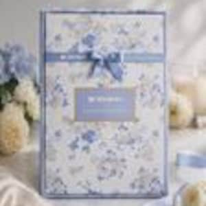 May include: A rectangular gift box featuring a white background with a blue floral pattern. The box is adorned with a blue ribbon tied in a bow at the top centre and includes a rectangular blue label in the middle with the text "MYSTERY BOX".