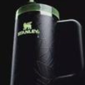 Puede incluir: Un vaso Stanley negro con acabado mate, que presenta una tapa verde y un logotipo verde a juego en la parte frontal. La taza incluye un asa lateral resistente y una pajita que sobresale por la parte superior, con un sutil patr&oacute;n de hojas.