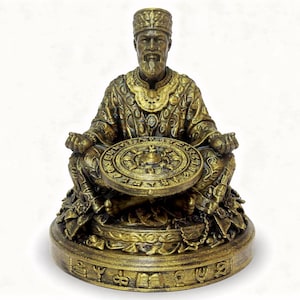 Könnte beinhalten: Detaillierte goldene Statue einer sitzenden Figur, geschmückt mit aufwendiger Kleidung und Kopfbedeckung. Die Figur hält ein kreisförmiges Objekt mit detailliertem Design. Die Statue steht auf einem runden Sockel mit eingravierten Symbolen.