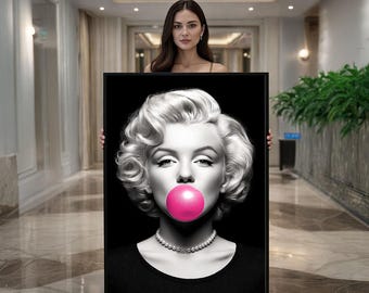 May include: Black and white portrait of Marilyn Monroe with a pink bubble gum bubble. She wears a black top and a pearl necklace. The image is framed in a black rectangular canvas.