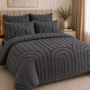 May include: A dark grey bedspread and pillow set. The bedding features an arched design with vertical lines. The bed is made up with a comforter, two pillow shams, and two decorative pillows. The bedroom has a neutral colour palette.