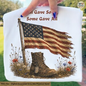 May include: White t-shirt featuring an American flag, a combat boot, and the text "All Gave Some, Some Gave All." The design includes wildflowers and a dog tag, evoking a patriotic theme.