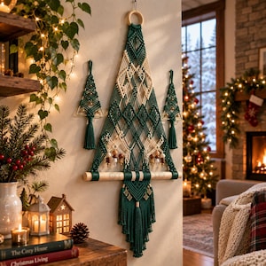 May include: A large triangular macrame wall hanging in dark green and cream cord, featuring a diamond pattern, wooden beads, and a bottom fringe. Two smaller matching macrame tree ornaments hang on either side of the central piece.