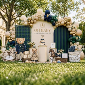 May include: A baby shower display featuring a large balloon arch in cream, gold, navy, and dark green. The setup includes a central arched backdrop with the text OH BABY, A Little Gentleman is on the Way, a tiered cake, teddy bear cutouts, and a carriage.