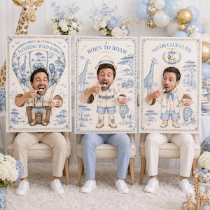 May include: Three rectangular photo booth props featuring blue and white toile safari illustrations. The left sign reads FLOATING WILD & FREE, the center BORN TO ROAM, and the right SAFARI CLUB CUTIE. Each board has a cutout for a face.