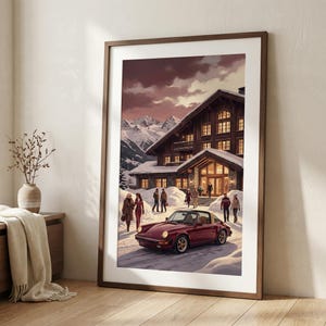 Könnte beinhalten: Gerahmter Kunstdruck, der eine Winterszene mit einem weinroten Sportwagen zeigt, der vor einem großen Holzchalet geparkt ist. Menschen gehen im Schnee. Schneebedeckte Berge sind im Hintergrund unter einem bewölkten Himmel. Der Druck ist in einem Holzrahmen.