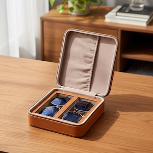 May include: Open, tan leather sunglasses case with two pairs of sunglasses inside. The case is rectangular with a zipper closure and a soft, beige interior. The sunglasses have blue lenses.