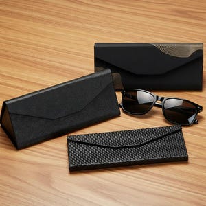 Puede incluir: Un surtido de gafas de sol y estuches negros sobre una superficie de madera. Las gafas de sol tienen lentes oscuras y una montura negra. Hay tres estuches diferentes, dos rectangulares y uno triangular. Los estuches son negros con superficies texturizadas y cierre de solapa.