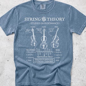 May include: A blue short-sleeve t-shirt featuring a white graphic print titled String Theory Studies in Resonance. The design includes illustrations of a violin, viola, and bass with labels, a wave diagram, and text detailing variables and results.