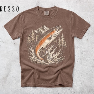 K&ouml;nnte beinhalten: Ein espressofarbenes Kurzarm-T-Shirt mit einem Grafikdruck eines aus dem Wasser springenden Fisches. Das Design zeigt im Hintergrund ein Gebirge und Tannenb&auml;ume in wei&szlig;en und orangefarbenen T&ouml;nen. Der Text ESPRESSO ist auf dem Bild zu sehen.