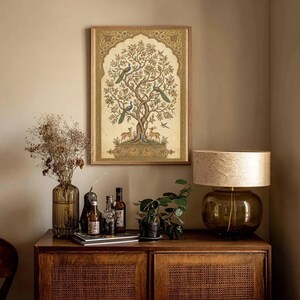 May include: A rectangular wall art print featuring a detailed illustration of a large tree with peacocks and deer, enclosed in an ornate golden archway border. The artwork displays a muted color palette of gold, brown, and green tones on a cream background.