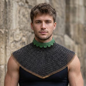 May include: A chainmail gorget featuring a dark metallic mesh construction with a scalloped green leather collar trim. The piece is finished with a decorative gold-toned metal ring border along the bottom edge, creating a structured neck and shoulder covering.