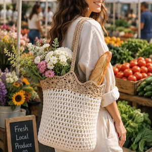 May include: A cream-colored crochet tote bag with a tan crochet trim, filled with flowers and a baguette. The bag is carried over the shoulder. A chalkboard sign reads "Fresh Local Produce".