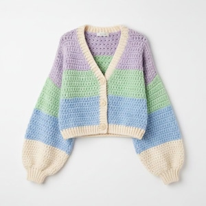 Puede incluir: Un cárdigan de ganchillo de color pastel con cuello en V y cierre de botones. El suéter presenta rayas horizontales de lavanda, verde menta y azul claro, con ribetes y mangas color crema. Las mangas son estilo globo.