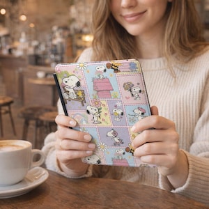 May include: A colorful tablet case featuring Snoopy and Woodstock characters in a patchwork design. The case has a black border and a variety of pastel squares with Snoopy in different poses, flowers, and Snoopy's doghouse.