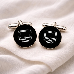 May include: Silver cufflinks with a black circular face, each bearing a white outline of a computer monitor. The cufflinks are presented on a white, textured fabric.
