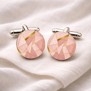 May include: A pair of round cufflinks featuring a geometric pattern of pink textured segments separated by thin gold lines. The cufflinks have a polished silver-tone metal backing with a standard swivel toggle mechanism for secure fastening.