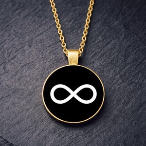 Può includere: Collana color oro con un ciondolo rotondo con un simbolo dell'infinito bianco su sfondo nero. La catena e la cornice del ciondolo hanno una finitura lucida. La collana è presentata su una superficie scura e strutturata.