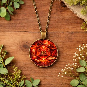 Può includere: Una collana con pendente color bronzo con un ciondolo rotondo e dettagliato. Il ciondolo presenta una scena fantasy rossa e arancione con un drago, un castello e un dado luminoso con il numero 20. La collana è esposta su una superficie di legno.