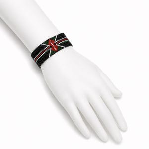 May include: A wide beaded cuff bracelet featuring a black background with a geometric pattern in red, white, and green. The design consists of small, uniform beads arranged in a structured, symmetrical layout that wraps around the wrist area.