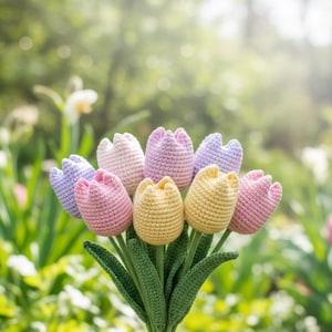 Op de afbeelding: Een boeket handgemaakte gehaakte tulpen in verschillende pastelkleuren, waaronder roze, geel, lavendel en wit. De tulpen hebben groene stelen en bladeren, tegen een vage groene achtergrond.