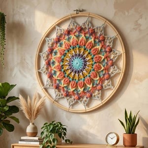 Può includere: Un arazzo da parete mandala all'uncinetto colorato e fatto a mano. Il design circolare presenta una vibrante gamma di colori tra cui blu, arancione, giallo e grigio. Il mandala è incastonato in un telaio da ricamo in legno naturale.