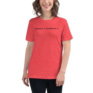 Op de afbeelding: Rood t-shirt met de zwarte tekst "Engineer 9-5, Cats Mom 24/7". Het shirt heeft een relaxte pasvorm en korte mouwen. Het model draagt een zwarte broek.