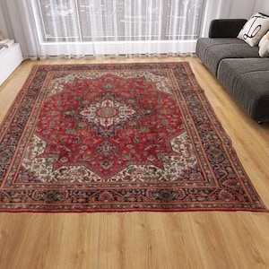 May include: A rectangular, ornate red rug with a central medallion design and intricate border patterns. The rug features a rich color palette of red, cream, and dark accents, adding warmth to the room. The rug is placed on a wooden floor.